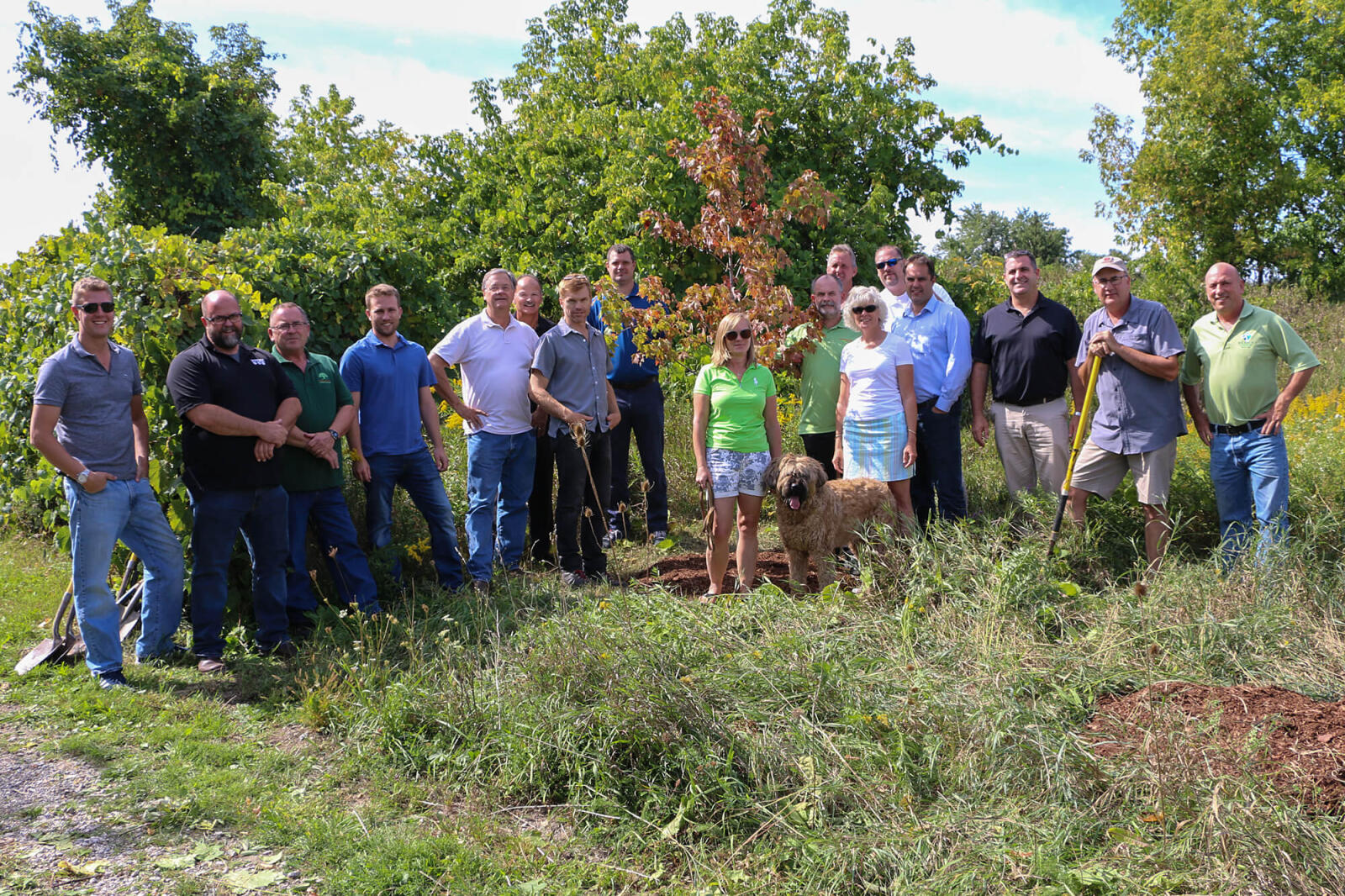 LO boar members surround a newly planted tree