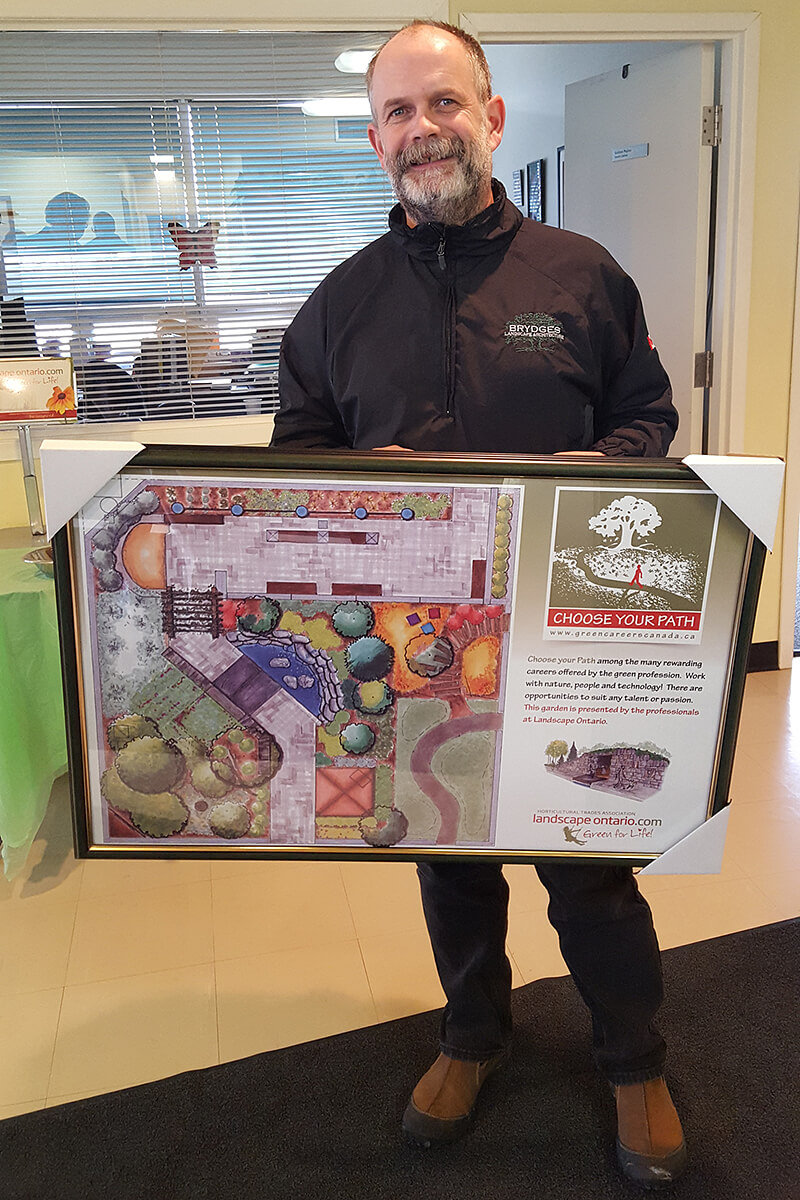 paul brydges holding a framed print of his garden design