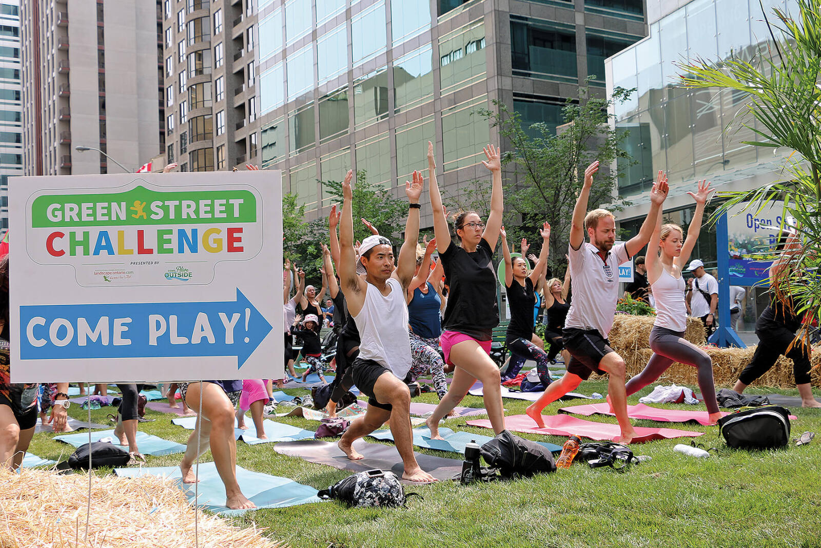 people doing yoga on a downtown street covered in grass