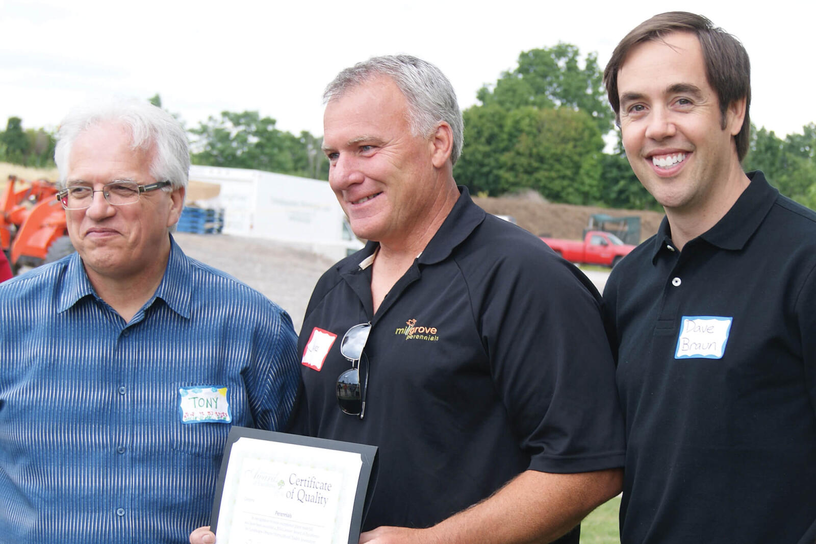 three men. middle on holding a certificate