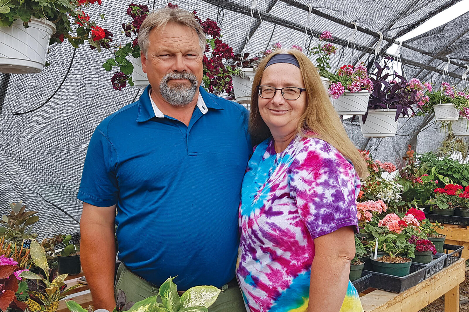 man and woman in a greenhouse with plants
