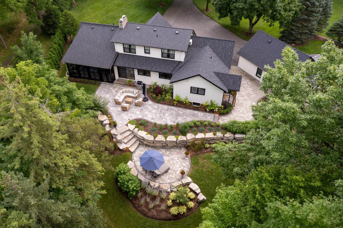 a large home by the water with extensive landscaping on a hillside